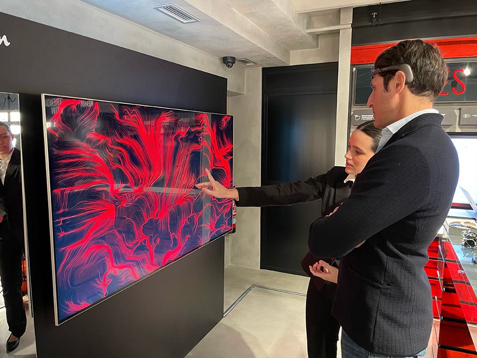 Partecipante con dispositivo EEG osserva la propria opera BrainArt® rossa generata in tempo reale su grande schermo